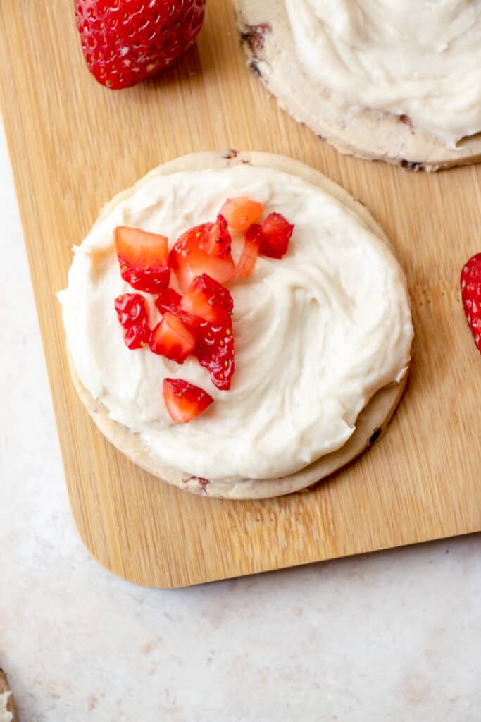 Overhead view of a strawberry sugar cookie topped with icing and chopped strawberries