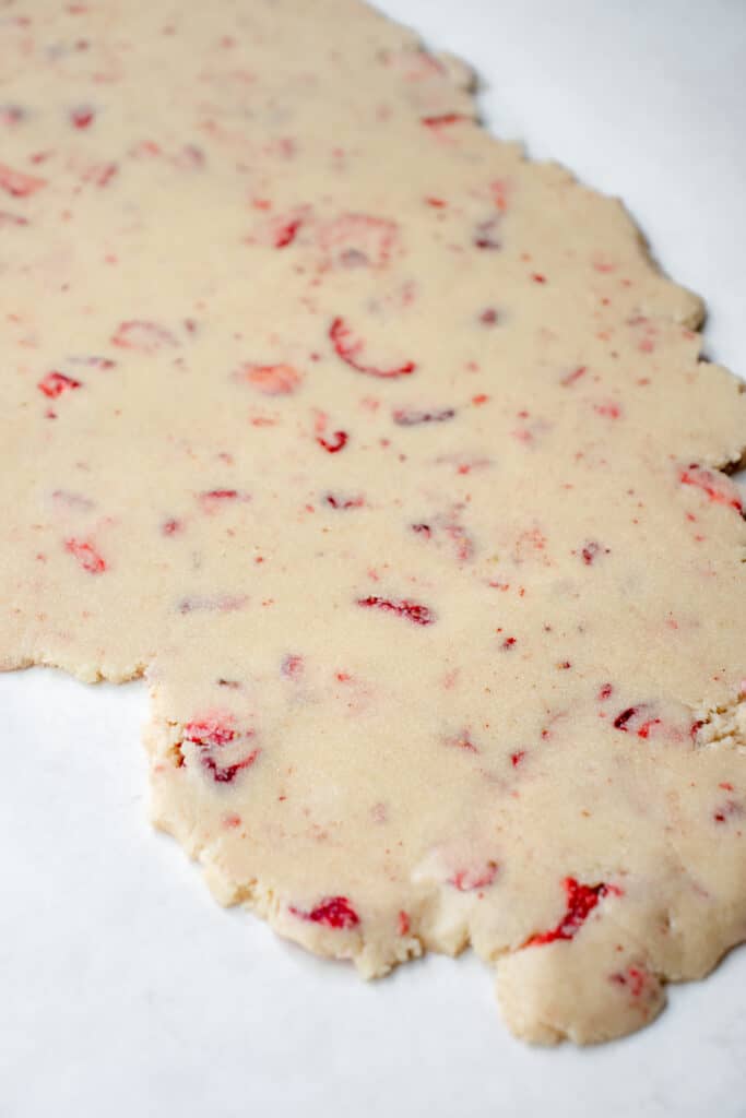 Strawberry cookie dough rolled out into a rectangle on parchment paper.