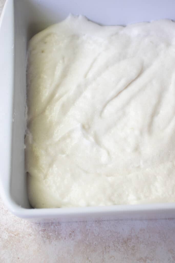 A white baking dish with gluten-free marshmallow mixture poured in.