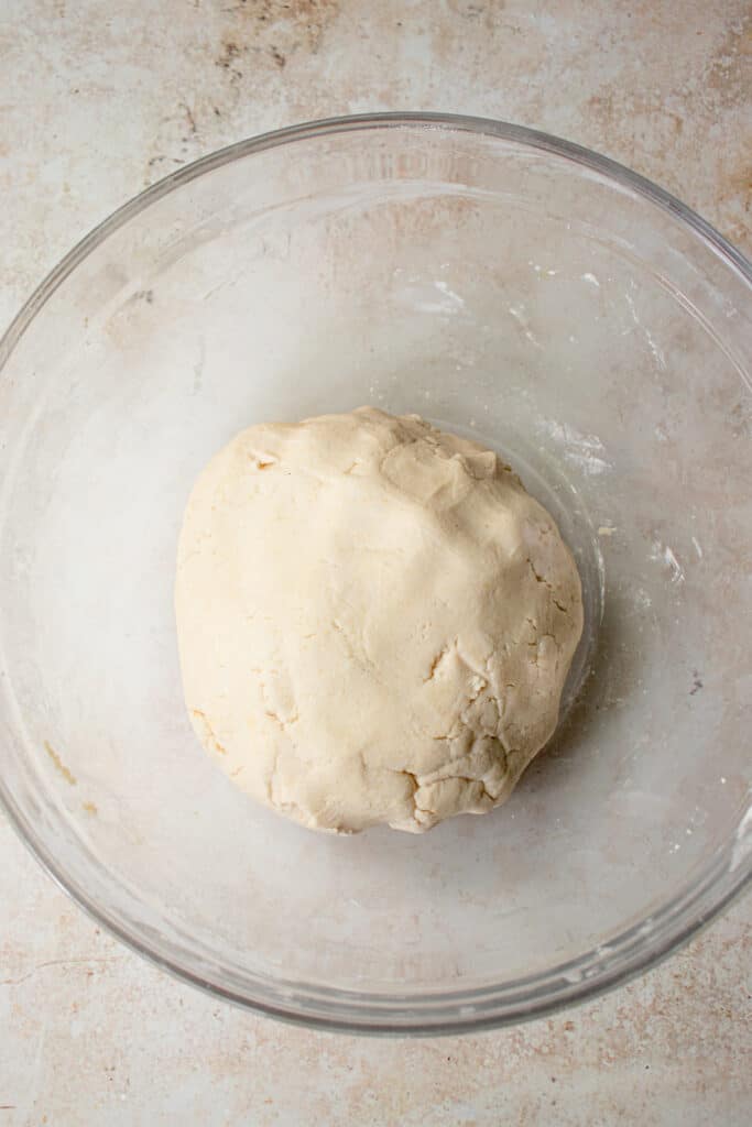 A glass bowl with a large ball of dough.