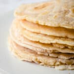 A close up shot of a stack of cassava flour tortillas on an off-white plate.