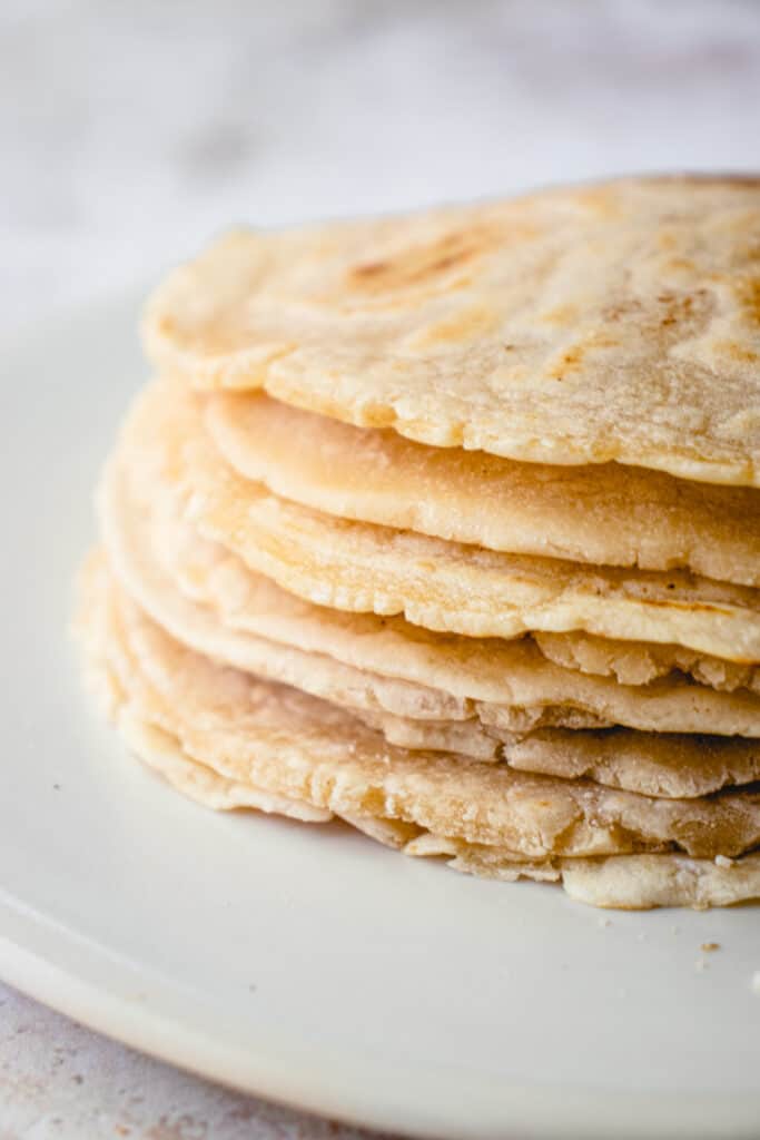 A close up shot of a stack of cassava flour tortillas on an off-white plate.