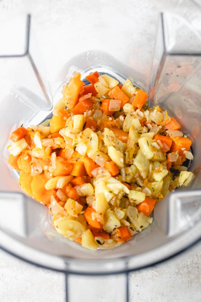 Overhead shot of sautéed herbed vegetables in the blender container of a Vitamix.