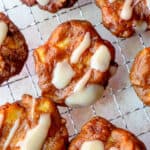 Maple glazed Gluten Free Apple Fritters on a wire cooling rack with parchment paper underneath.