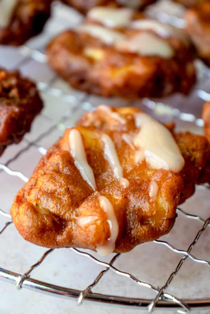 Close up of a Gluten Free Apple Fritter on a wire cooling rack, drizzled with maple glaze.