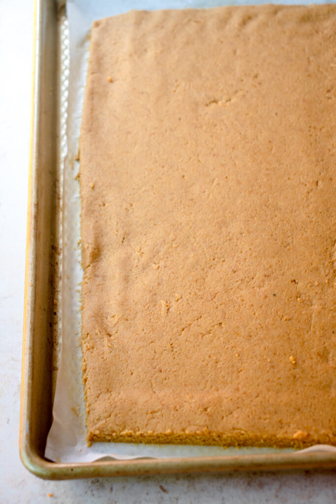 Pumpkin Roll dough in a rectangle on a baking tray lined with parchment paper.