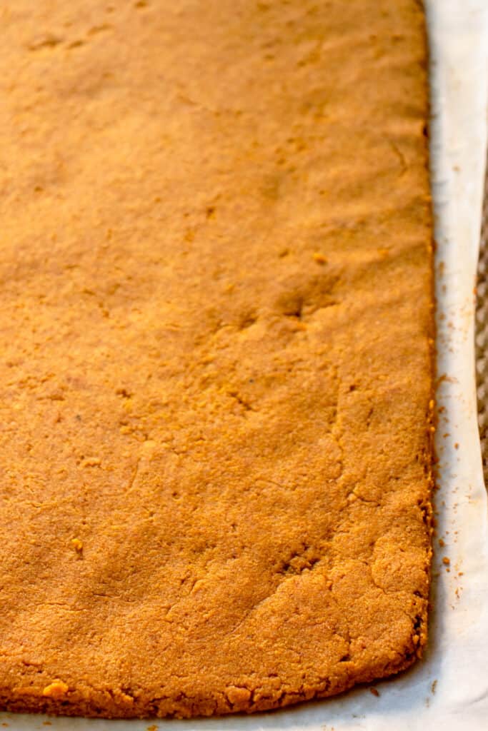 Baked Pumpkin Roll dough on a parchment paper lined baking tray.