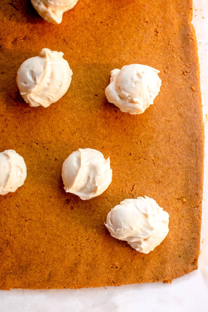 Dollops of cream cheese filling on the pumpkin roll cake.