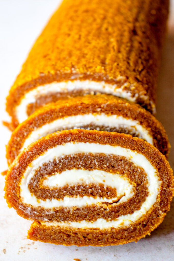 Gluten-free Dairy-free Pumpkin Roll with two slices in the front of the log.