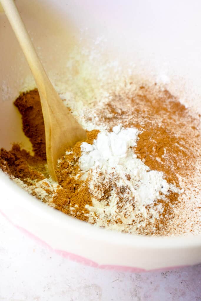 A large bowl with the dry ingredients and a wooden spoon, about to mix them together.