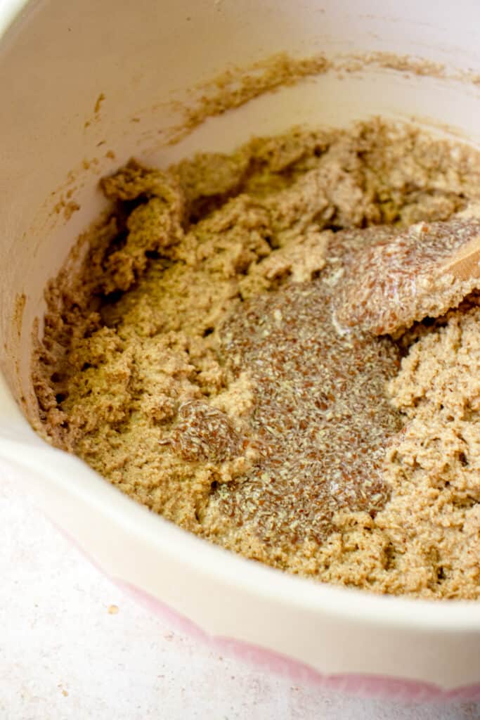 A large bowl with a flax egg poured into the donut batter, before being folded in.