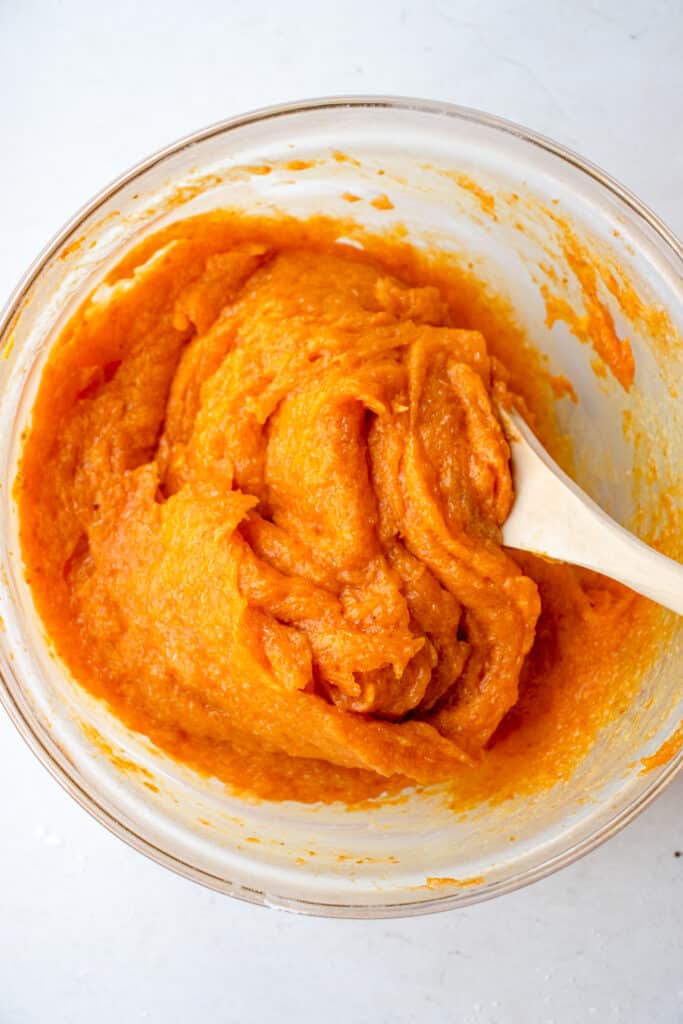 Pumpkin purée and remaining wet ingredients mixed together with the psyllium gel mixture with a wooden mixing spoon in a medium-sized glass bowl.