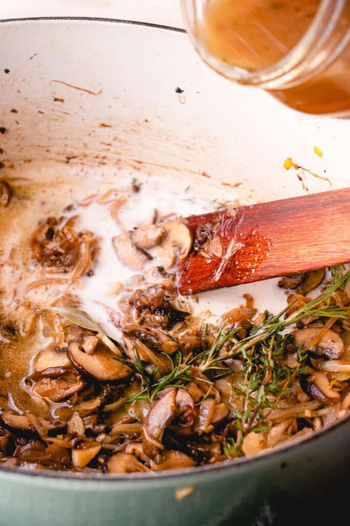 French oven with sautéed onions, leeks, garlic, mushrooms, sprigs of fresh rosemary, thyme, whole bay leaves, and coconut cream.