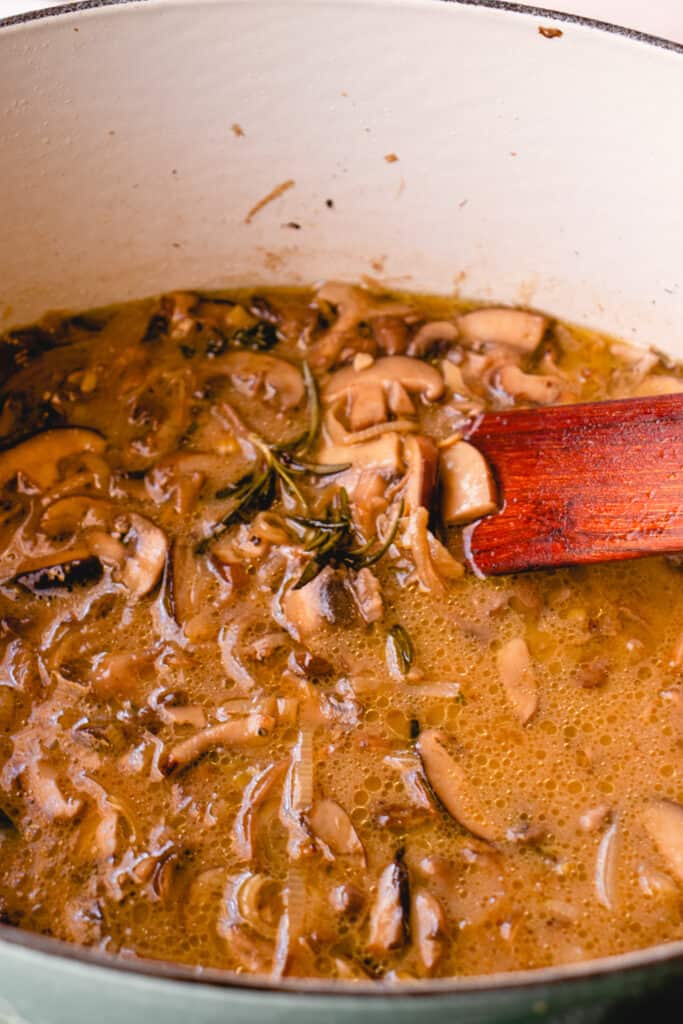 Simmered cream of mushroom soup in a French oven with a wooden flat sauté spatula in the pot.