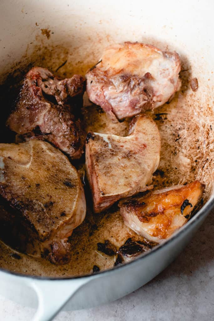 Caramelized beef bones in olive oil in a large pot.