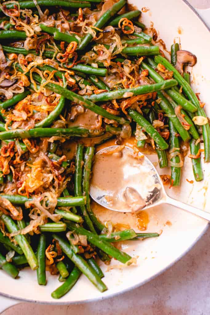 Baked Gluten-Free Green Bean Casserole in a braiser with a silver serving spoon.