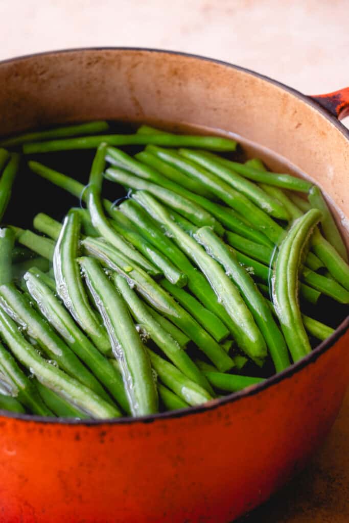 A large pot with water and fresh green beans.
