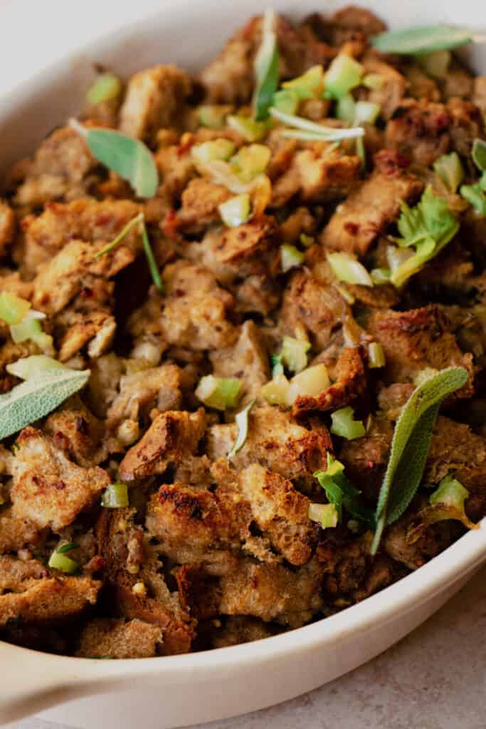 Close up of Gluten-Free Stuffing in a casserole dish garnished with diced celery and fresh herbs.