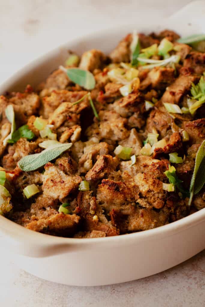 Close up of Gluten-Free Stuffing in a casserole dish garnished with diced celery and fresh herbs.