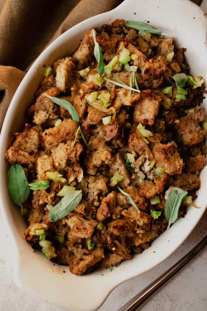 Gluten-Free Stuffing in a casserole dish garnished with diced celery and fresh herbs.