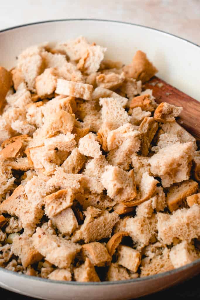 Torn pieces of bread added to the skillet with ground pork and vegetables.