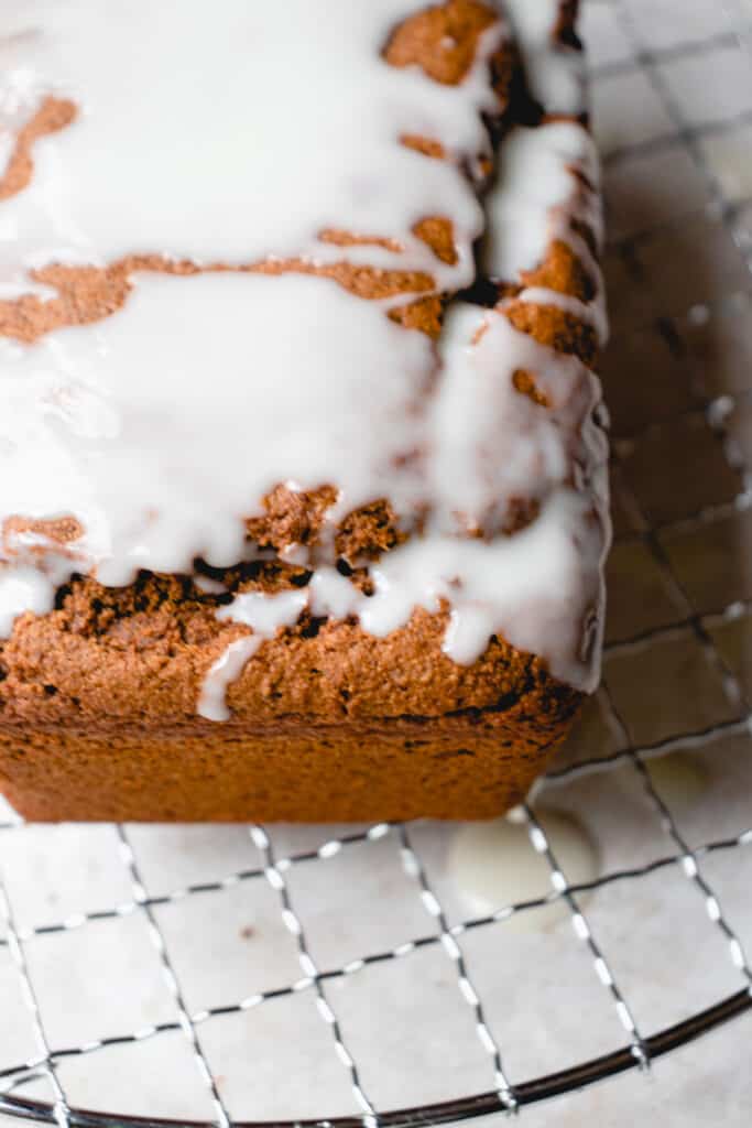 Gluten-Free Gingerbread Loaf drizzled with coconut glaze atop a cooling rack.