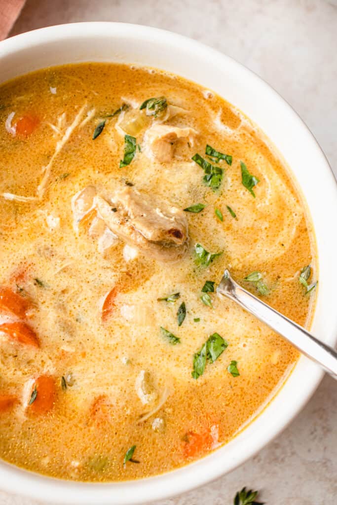 A close up of a bowl of the Gluten-free Dairy-free Creamy Chicken Soup with a silver spoon.