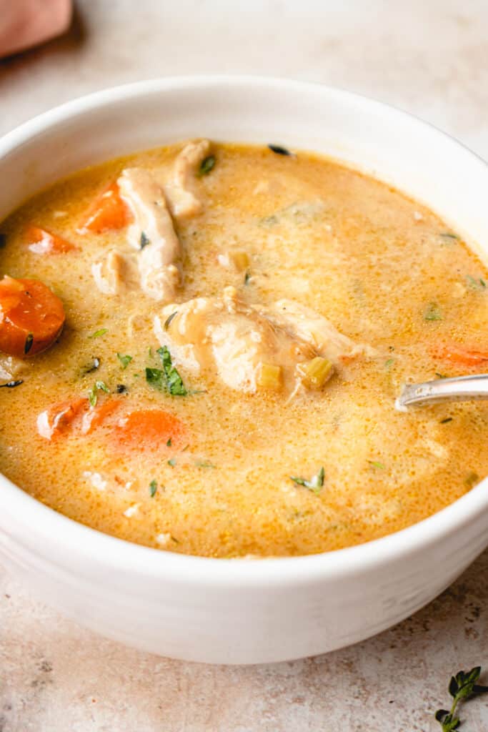 A bowl of Creamy Chicken Soup with a silver spoon.