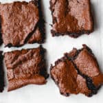 Overhead of Gluten-Free Vegan Brownies on parchment paper atop a wire cooling rack.