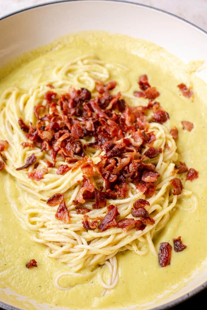 carbonara sauce in skillet topped with grain-free spaghetti and bacon