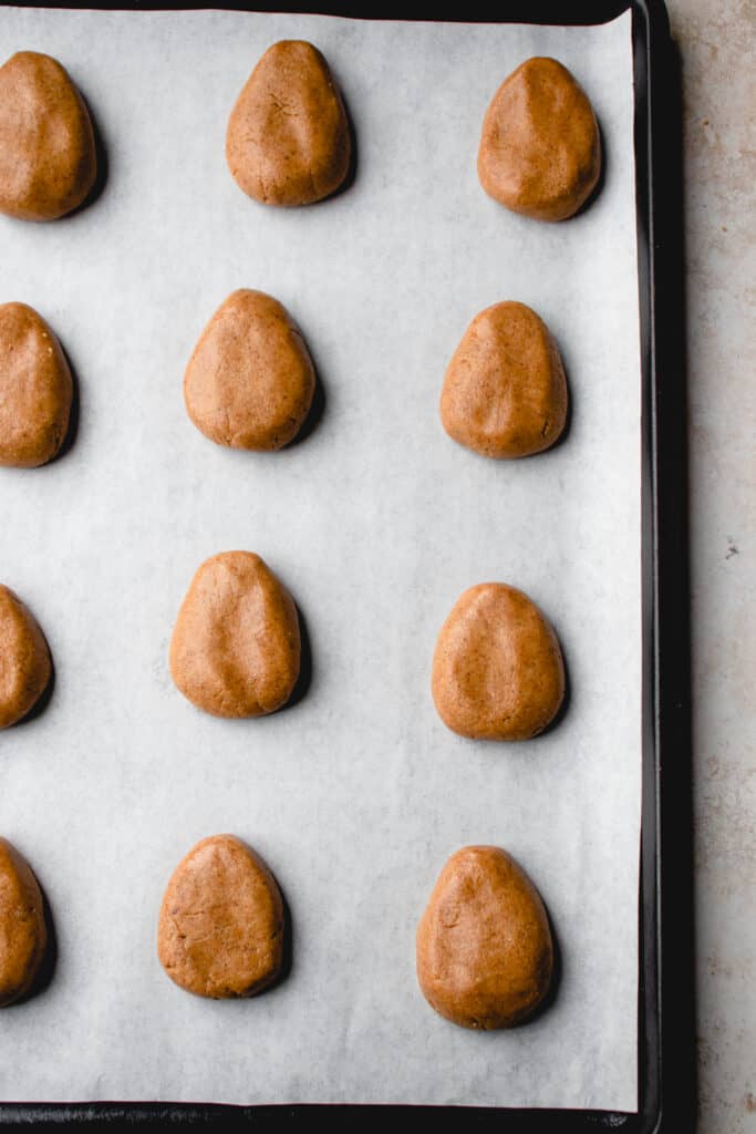 Shaped tahini-almond butter eggs arranged on a baking sheet lined with parchment paper.
