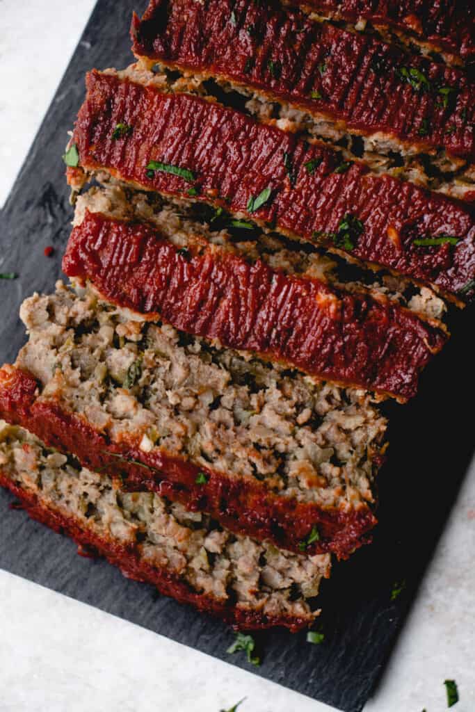 Slices of Dairy-Free Gluten-Free Meatloaf atop a slate cutting board.
