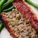 A plate with two slices on Dairy-Free Gluten-Free Meatloaf and green beans.