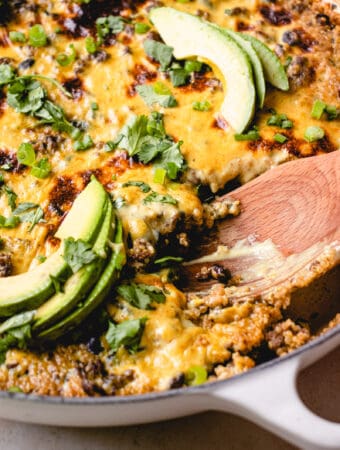 A wooden spatula scoops out some of the Easy Mexican Casserole from the braiser.