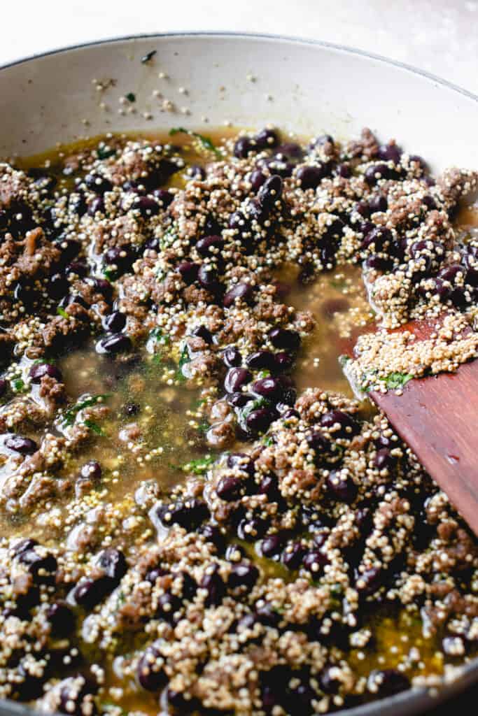 Black beans, quinoa, and bone broth are stirred into the seasoned ground beef.