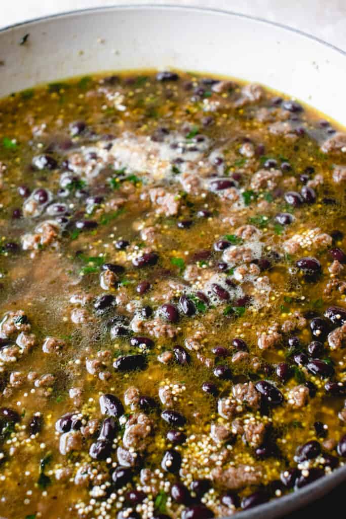 Black beans and quinoa are brought to a boil in the bone broth, stirred with the seasoned ground beef in the braiser.