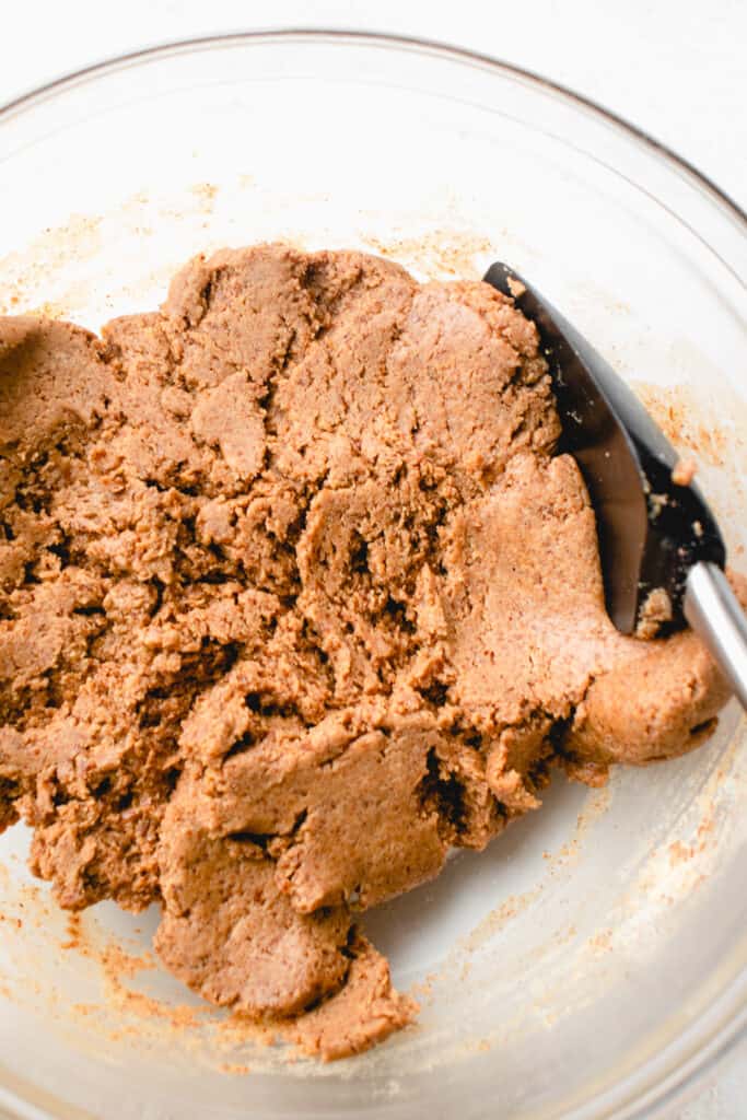 Protein bar 'dough' mixed together with a spatula in a large glass bowl.