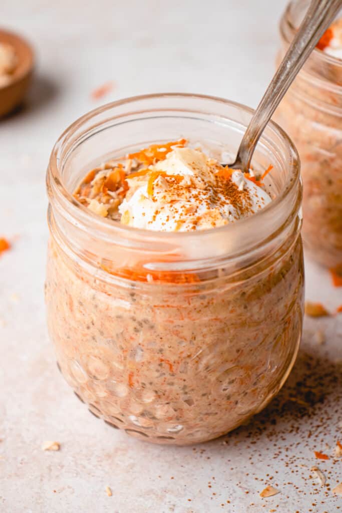 Close up of one jar with Vegan Carrot Cake Overnight Oats and a spoon.
