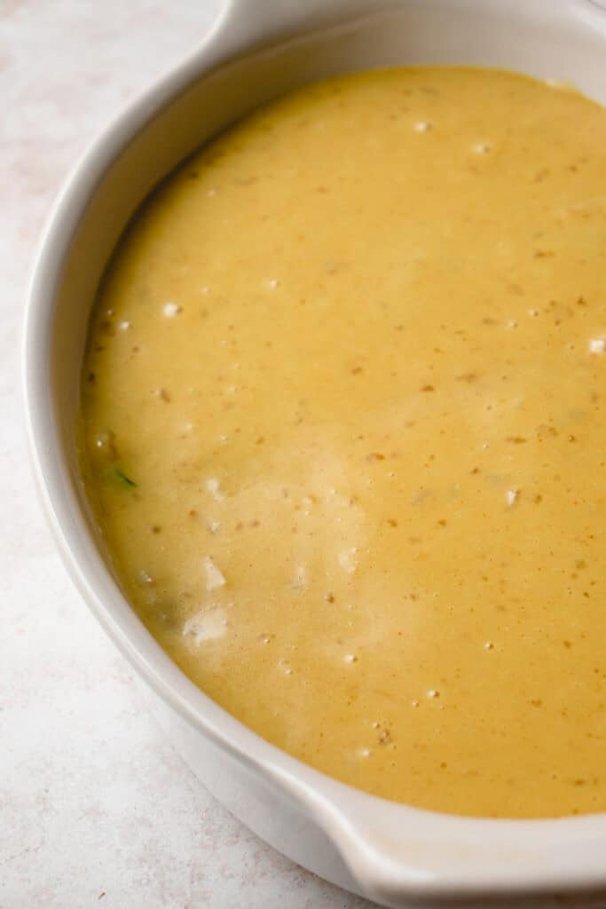 Dairy-free cheese sauce poured on top the creamy bean mixture in a baking dish.