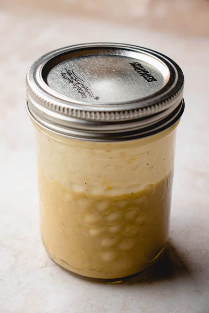 A mason jar with the Spring Pasta Salad dressing inside.