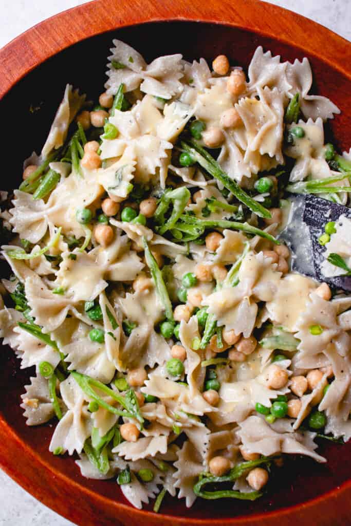 Sliced snap peas are added to the marinated pasta, green peas and chickpeas with additional dressing.