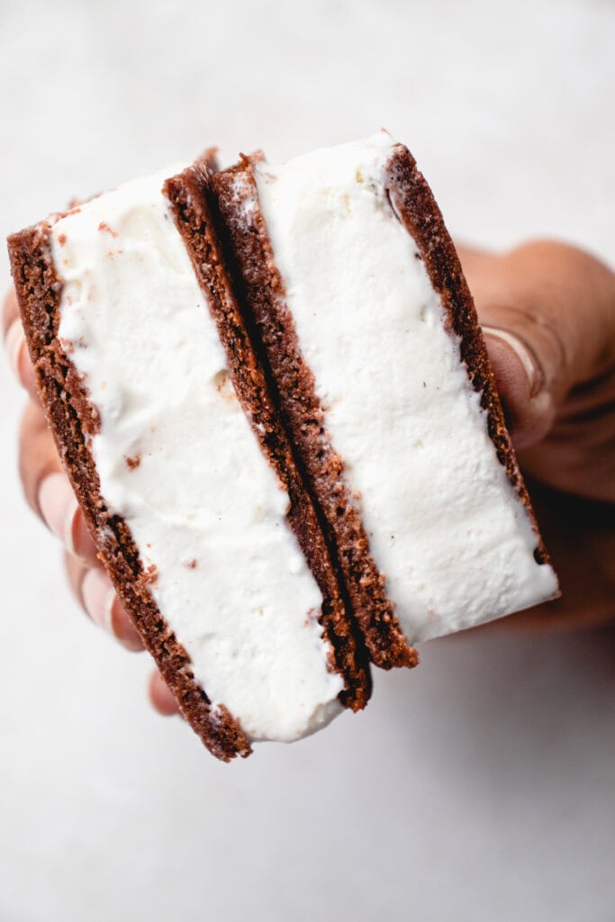 A brown hand holds two Gluten Free Dairy Free Ice Cream Sandwiches together.