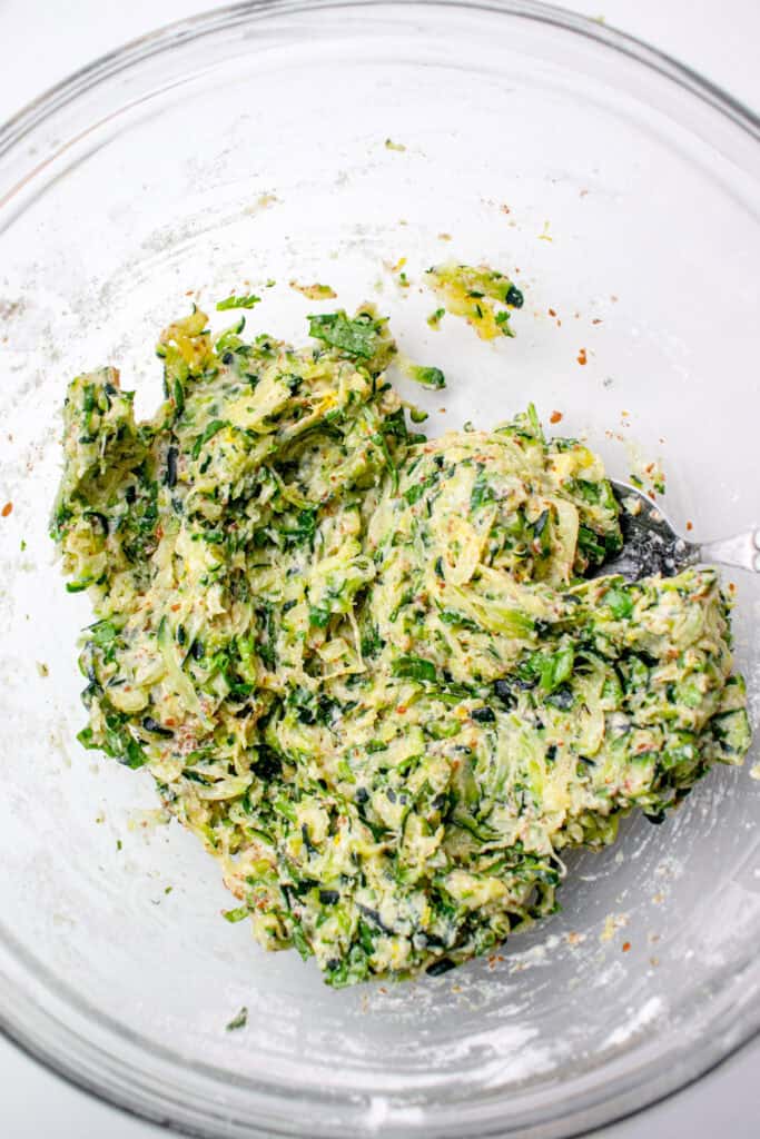 Gluten Free Zucchini Fritter batter in a large bowl, mixed together with a spoon.