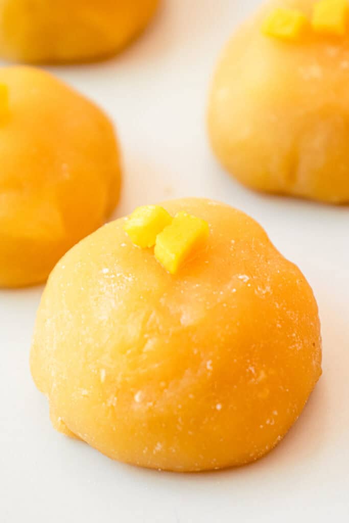 Close up of Mango Mochi on a plate, topped with two small cubes of fresh mango.