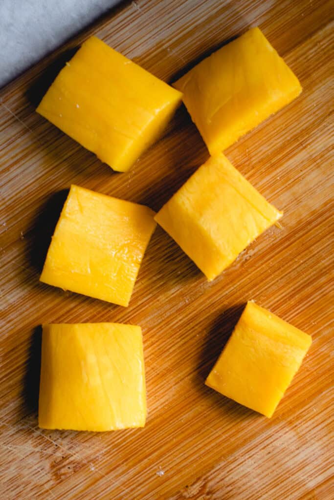 Mango cubes on a cutting board.
