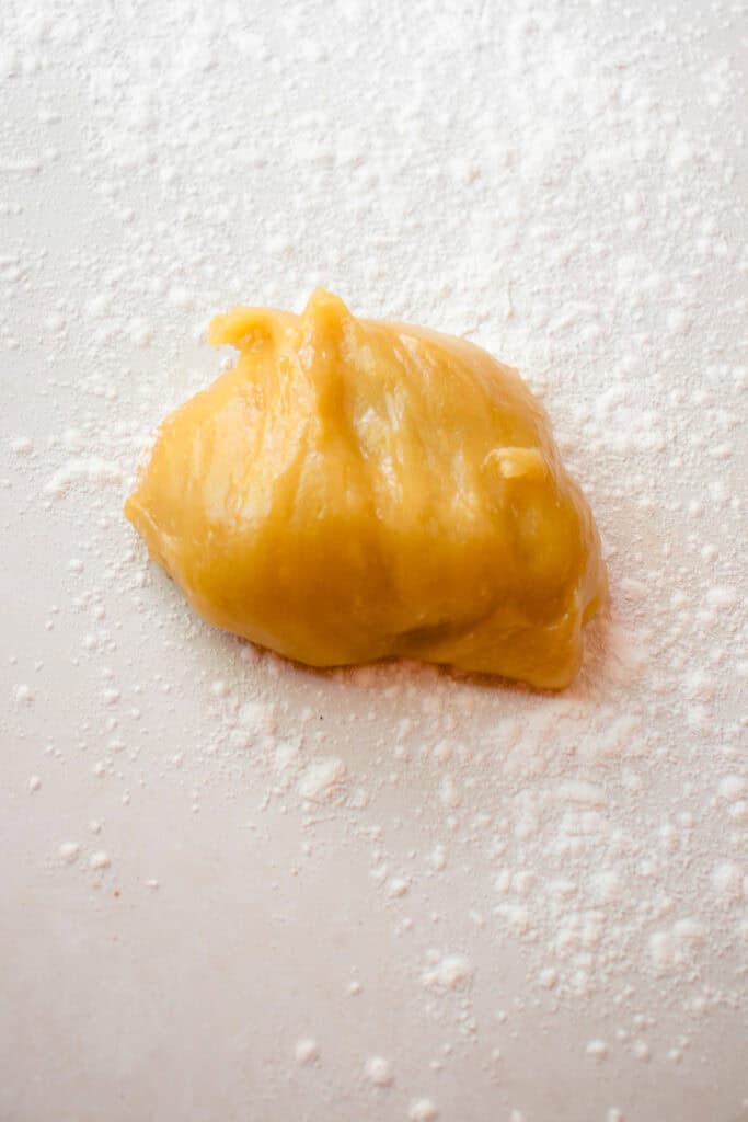 Mango mochi dough on a surface sprinkled with glutinous rice flour.