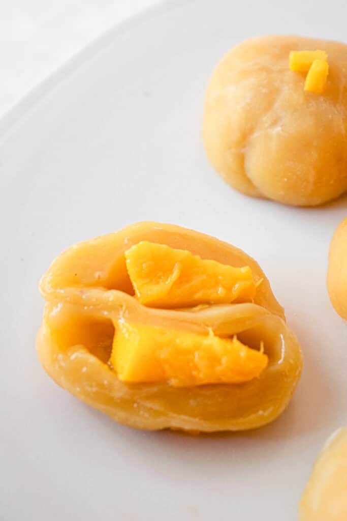 Close up of two halves of Mango Mochi to show the mango filling inside.