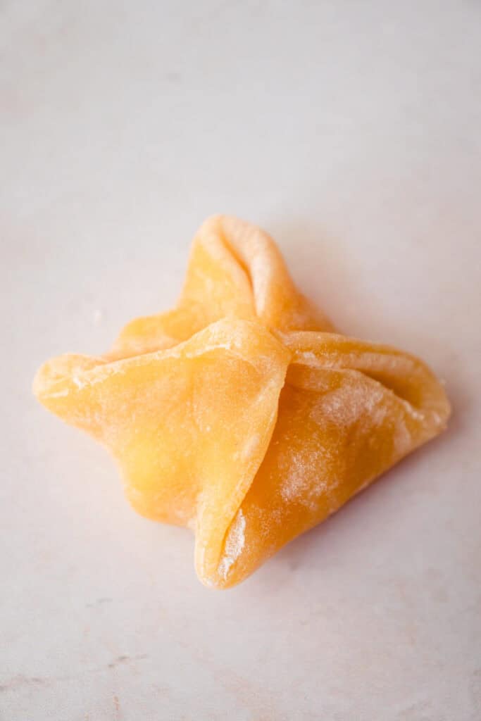 Folded mango mochi with the corners pinched together to seal it.