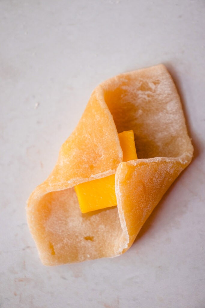 Folding the mochi dough over the cube of mango.