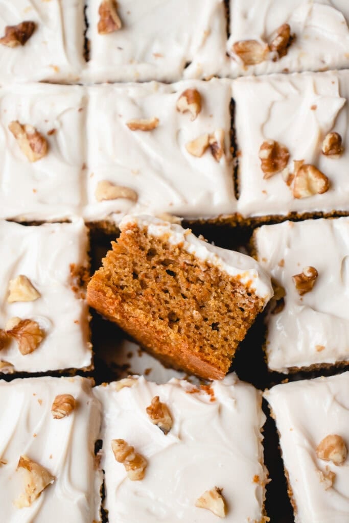 Overhead close up of squares of frosted cake with one piece on its side.